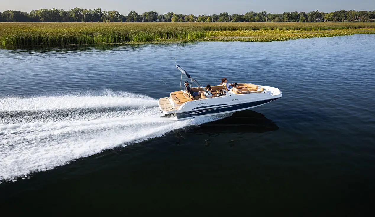 Side profile of a SunDeck Sport I/O 201 deck boat cruising across a lake.