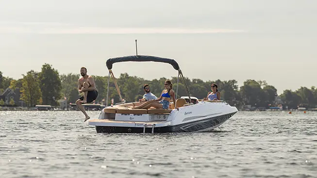 Man jumping off the swim platform while his friends watch on a Hurricane SunDeck Sport I/O deck boat.