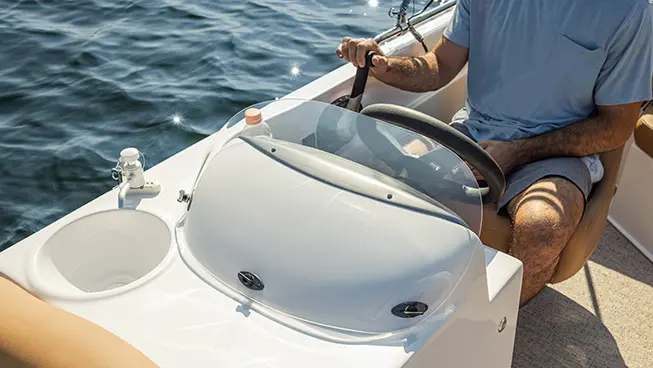 Closeup of the windshield on the captain's helm of a Hurricane SunDeck Sport I/O deck boat.
