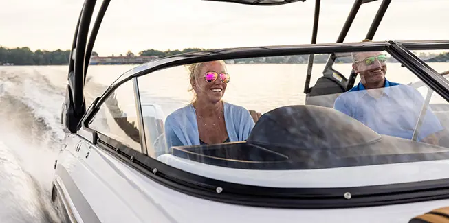 Woman smiling while steering a Hurricane yacht certified deck boat on the ocean.