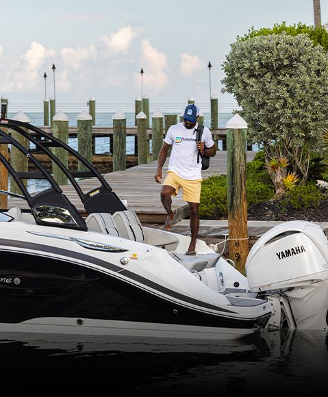 Man stepping onto deck boat while carrying a Hurricane backpack cooler. 