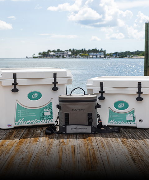 Hurricane branded coolers in various colors and sizes sitting on a dock near water. 