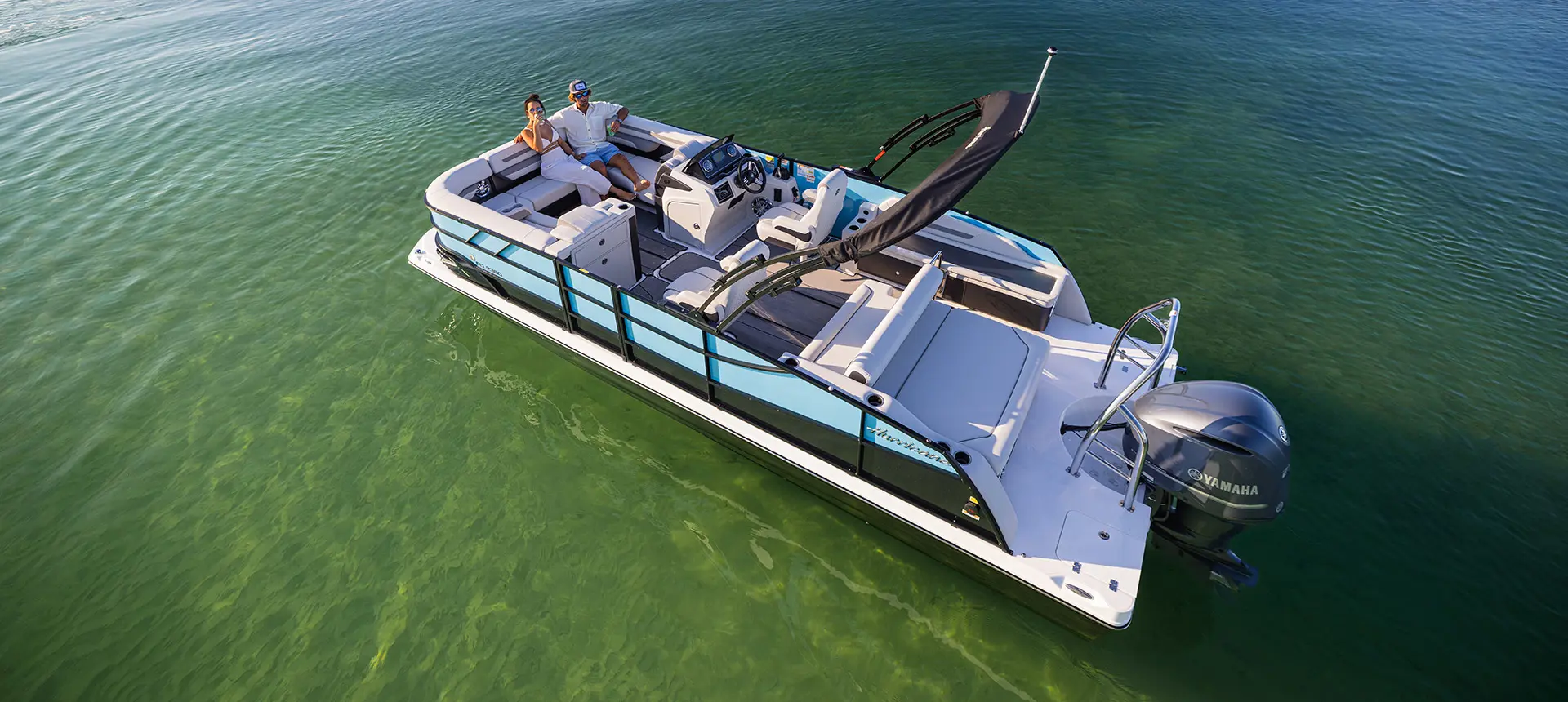 Aerial view of 2 people relaxing on the bow of a Hurricane Entertainment deck boat.