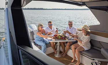 4 people enjoying a snack at the stern table on a Hurricane Entertainment deck boat.