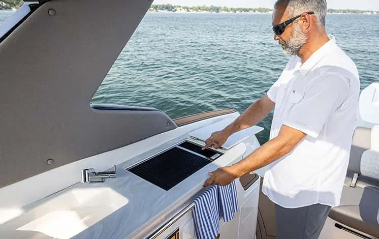 Man using the stove on a Hurricane Entertainment deck boat.