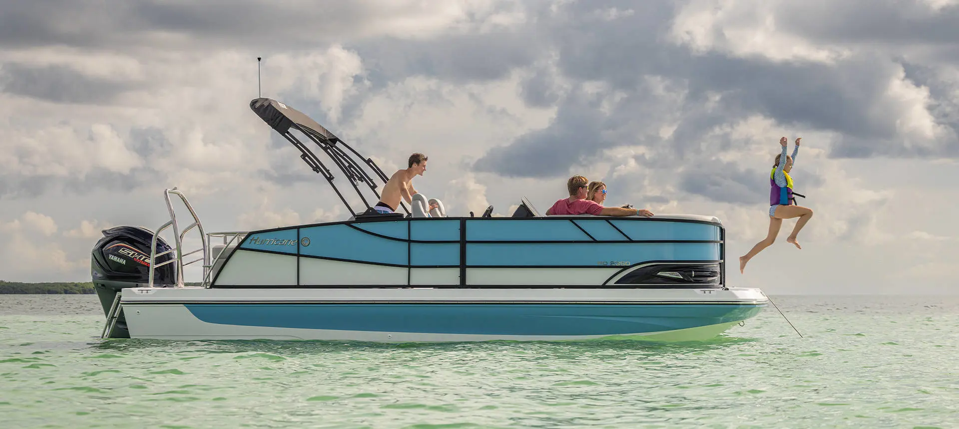 A kid in a lifejacket jumping off the bow of a Hurricane FunDeck deck boat in to the water.