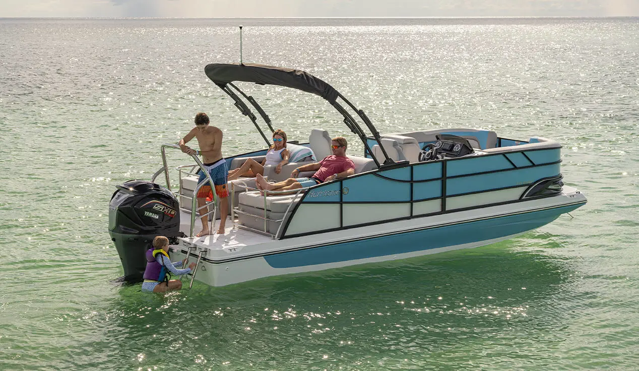 A girl climbing the stern ladder onto a Hurricane FunDeck deck boat while her family watches.
