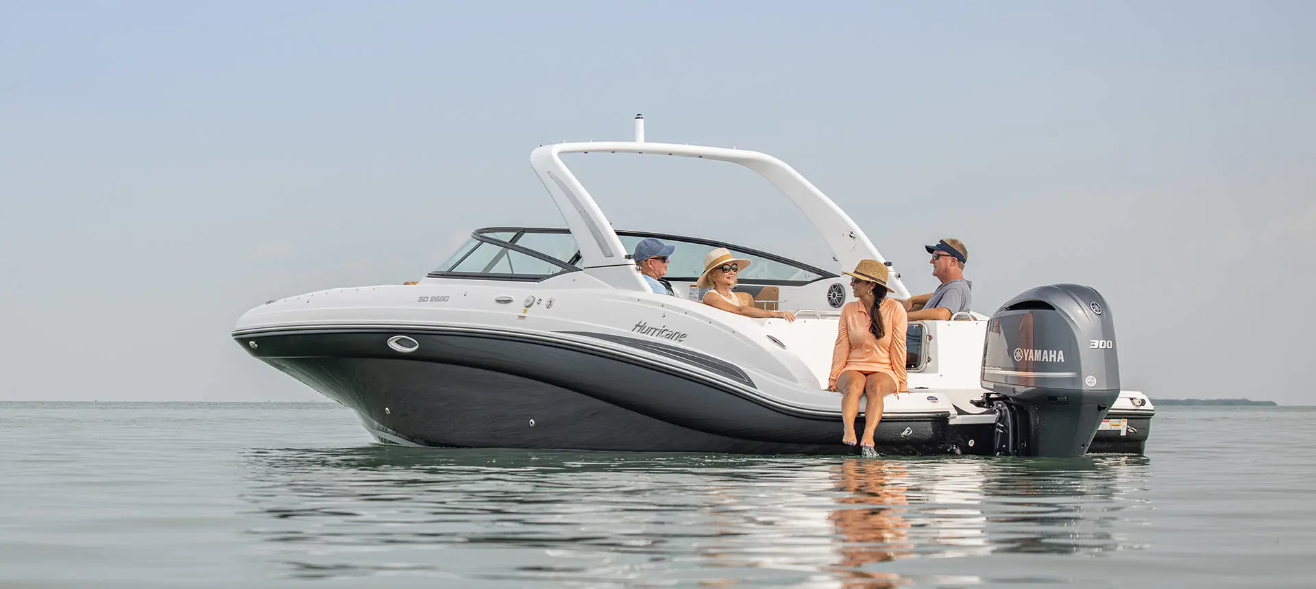 4 people relaxing on a Hurricane SunDeck OB deck boat while floating the lake.
