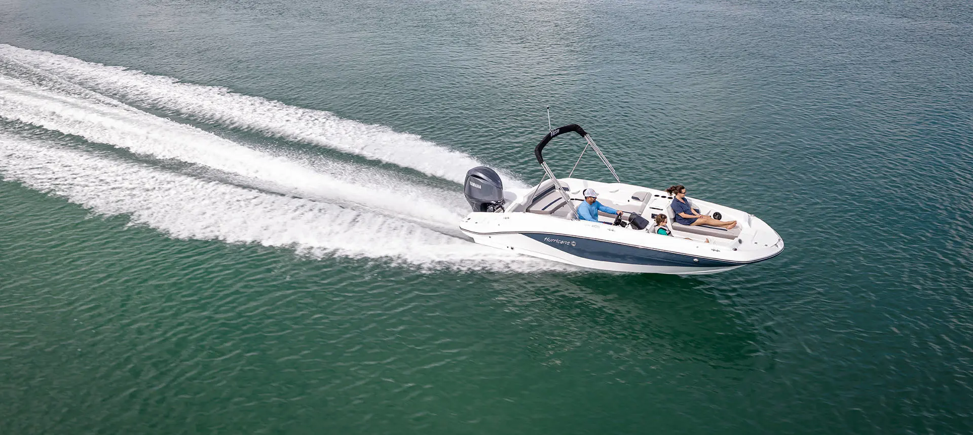 Aerial view of a Hurricane SunDeck Sport OB deck boat cruising across the ocean.