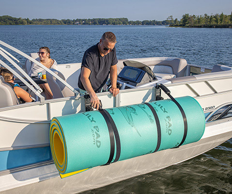 A boater attaching a swimming mat to the side of a deck boat using a rail attachment system