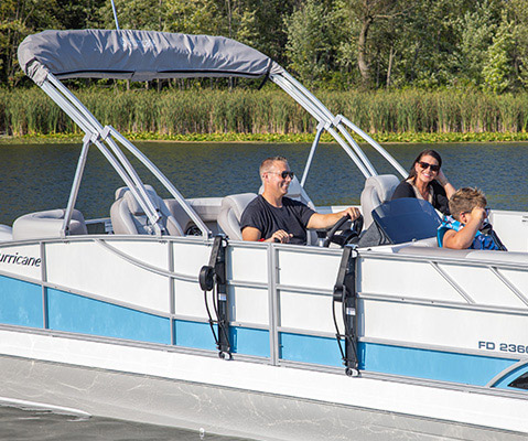Side profile of a Hurricane deck boat cruising on a lake, with a boat attachment system installed on the side of the exterior rails