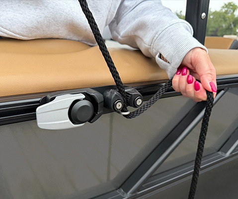 Close-up of a person adjusting a rope through a boat attachment system on the exterior rail of a Hurricane deck boat