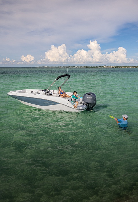 Dad and son playing with water toys off the back of a parked Hurricane Outboard deck boat.