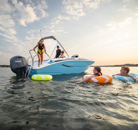 Kids playing with floaties on near a parked Hurricane Outboard deck boat.