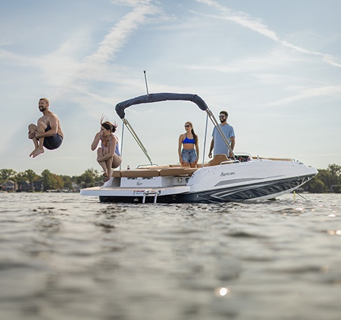 Man and woman doing cannonball off the back of a Hurricane Outboard deck boat.