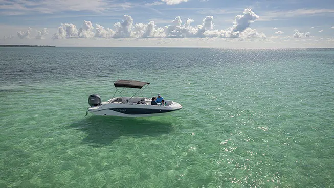 Side view of a Hurricane Outboard deck boat parked on the water.