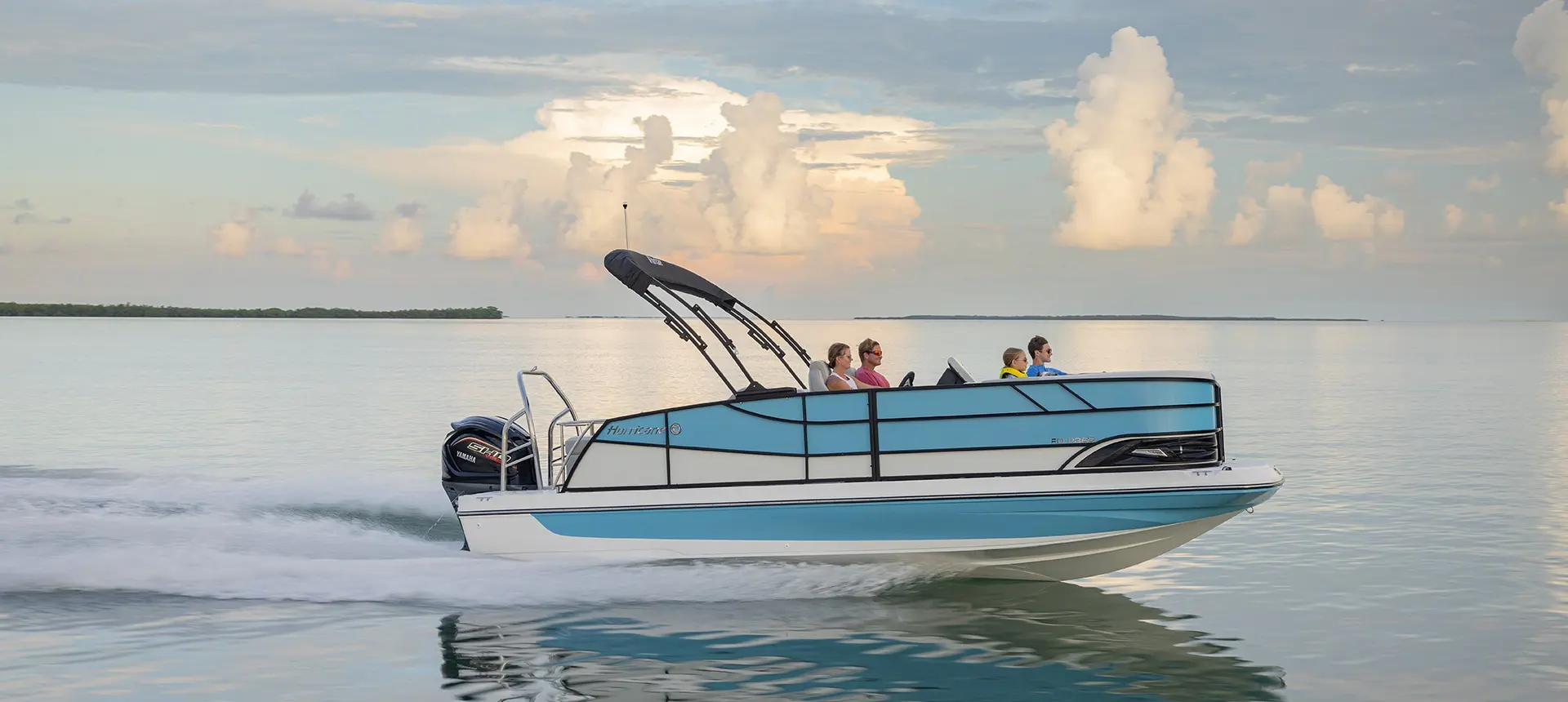 Side view of a Hurricane Outboard deck boat speeding across the water.