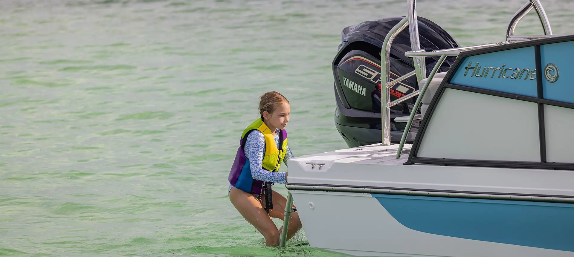 Girl climbing up ladder on a Hurricane Outboard deck boat.