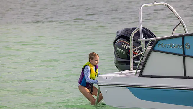 Girl climbing up ladder on a Hurricane Outboard deck boat.