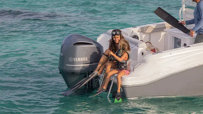 Kids putting on snorkling gear on the back of a Hurricane Outboard deck boat.