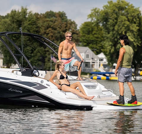 Man throwing tow rope for wakeboarding behind a Hurricane sterndrive io boat.