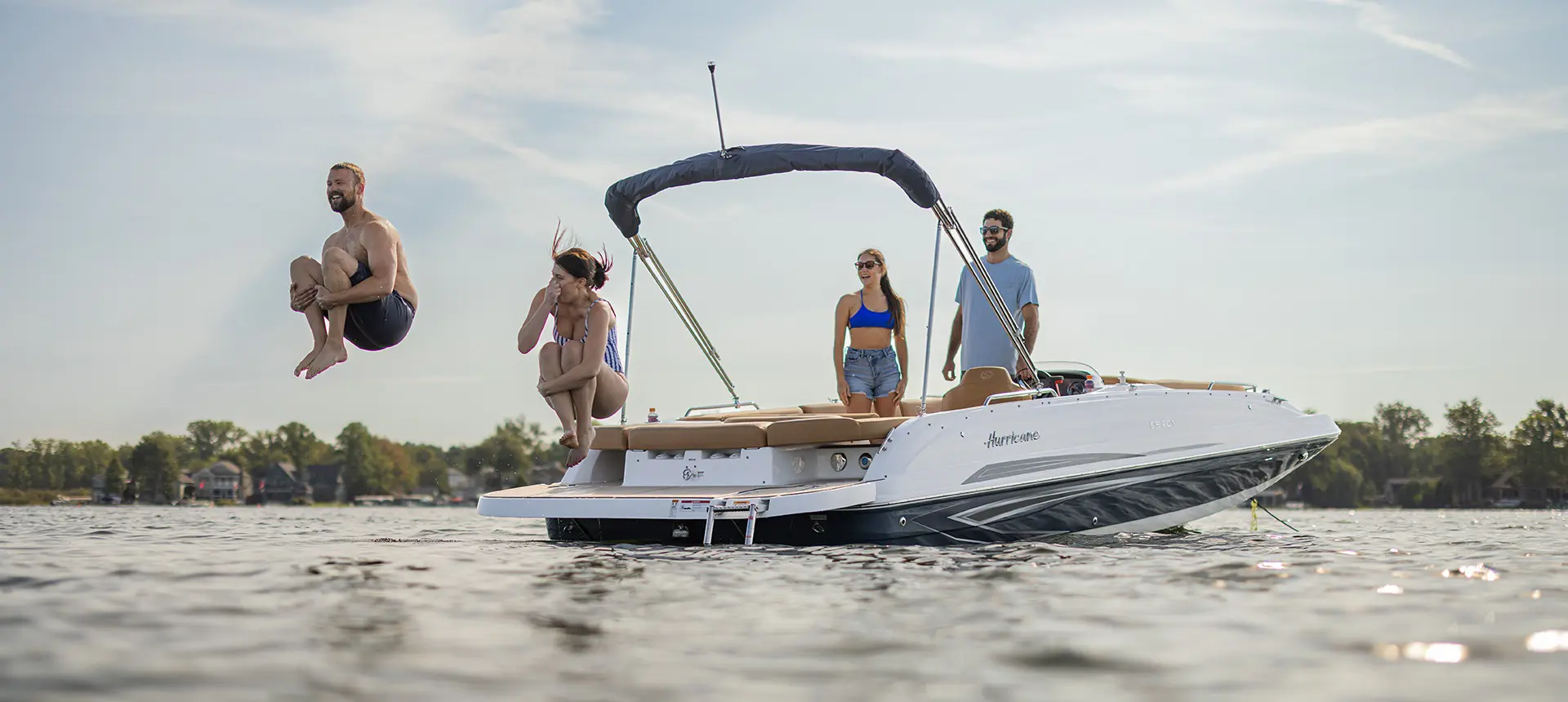 Man and woman doing cannonball off the back of a Hurricane sterndrive io boat.