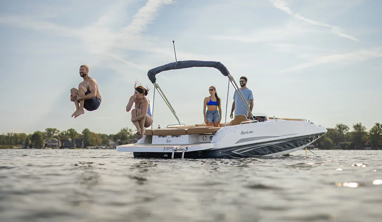 Man and woman doing cannonball off the back of a Hurricane sterndrive io boat.