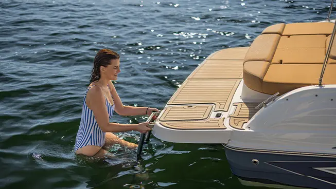 Woman climbing up ladder on a Hurricane sterndrive io boat.
