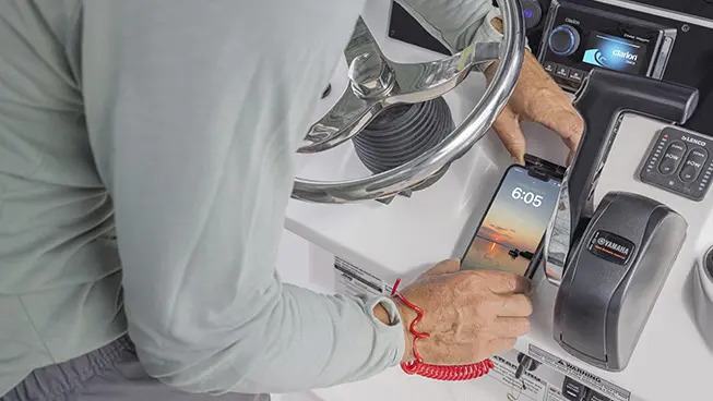 Man putting phone on charging dock station on a Hurricane Center Console boat.