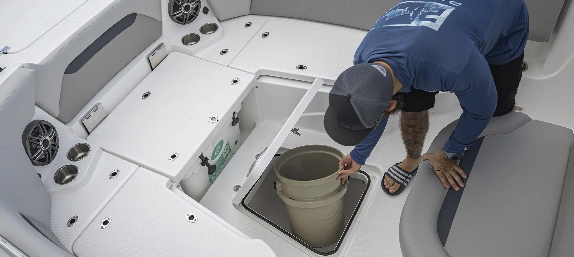 Man removing bucket from in-floor storage on a Hurricane Center Console boat.