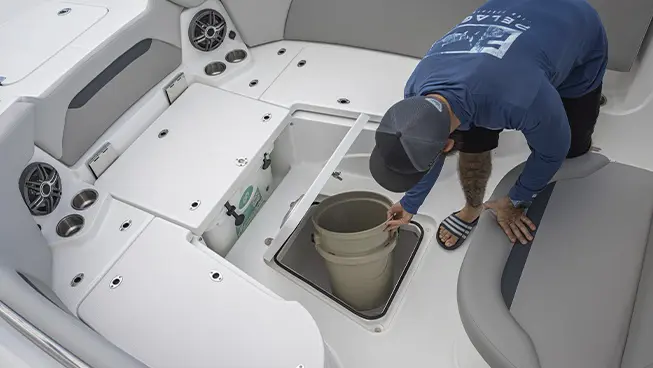 Man removing bucket from in-floor storage on a Hurricane Center Console boat.