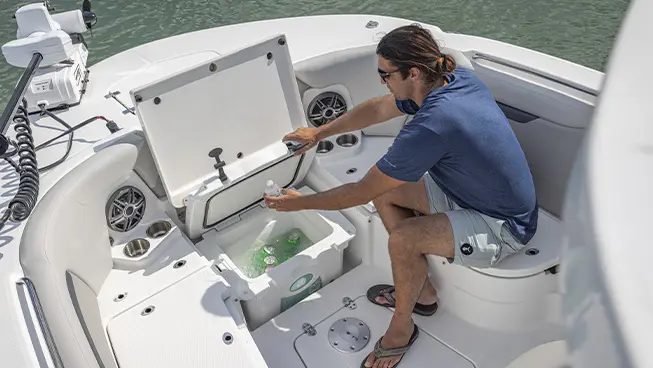 Man removing water bottle from cooler storage compartment on a Hurricane Center Console boat.
