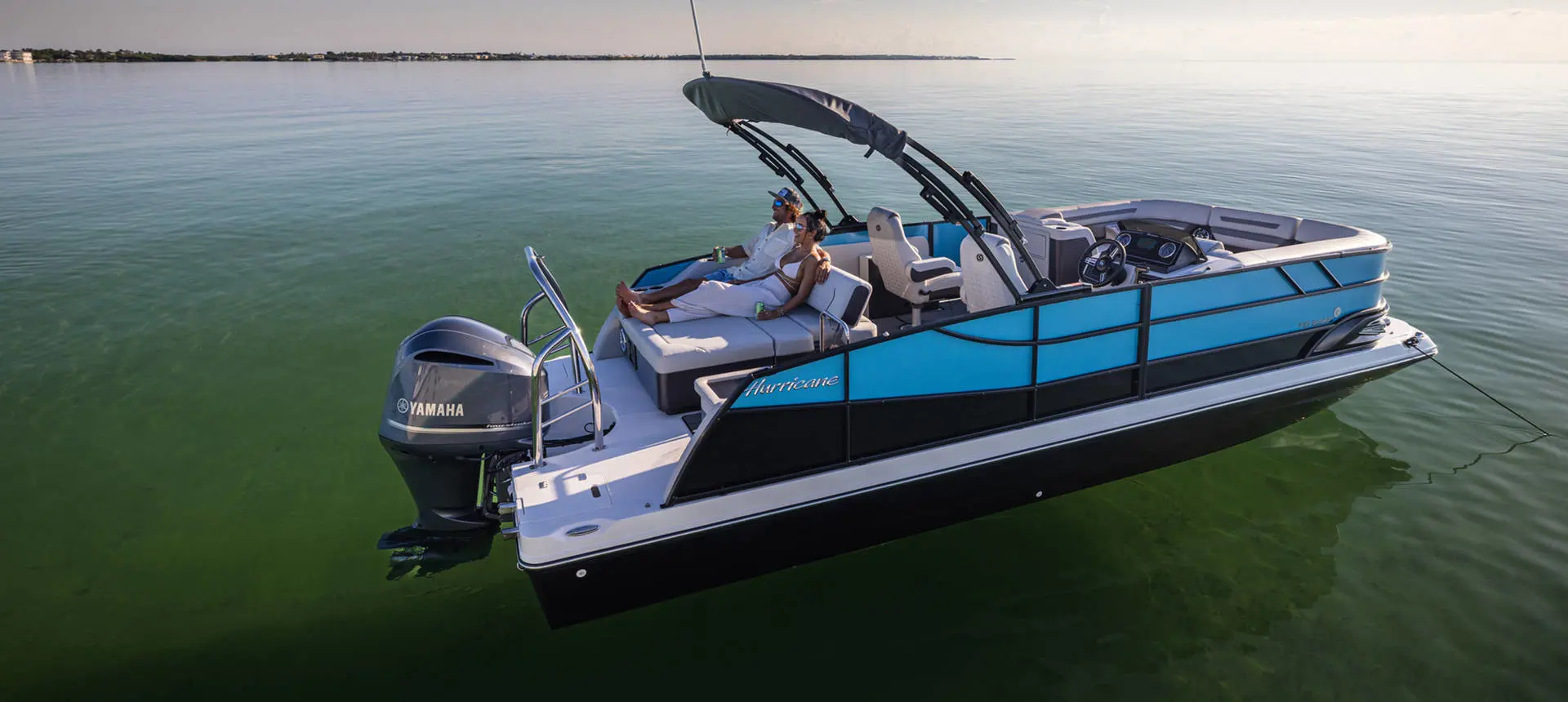 Man and woman relaxing on rear seating of a parked Hurricane FunDeck boat.