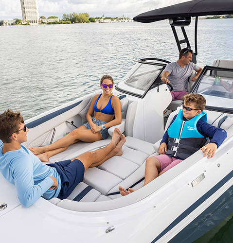 Family sitting in front deep-bow sitting on a Hurricane SunDeck 2600 Outboard boat.