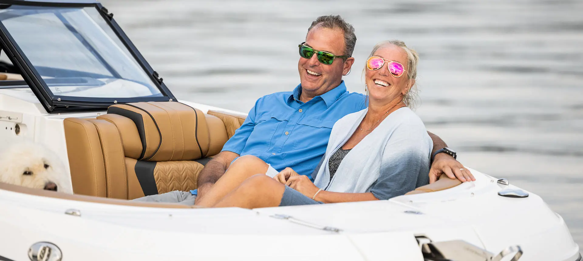 Couple smiling in the front seating of a Hurricane SunDeck 2600 Outboard boat.
