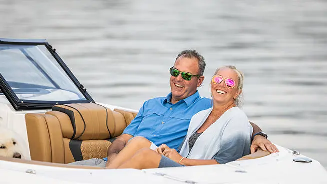 Couple smiling in the front seating of a Hurricane SunDeck 2600 Outboard boat.