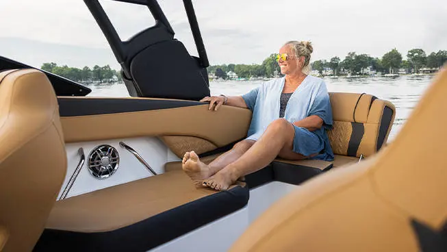 Woman sits on rear seating of a Hurricane SunDeck 2600 Outboard boat.