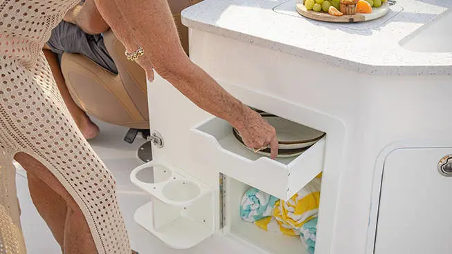 Woman removing plates from storage area on a Hurricane SunDeck 2690 Outboard boat.