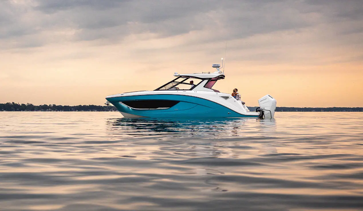 Side view of a Hurricane 3200 Outboard boat parked on the water.