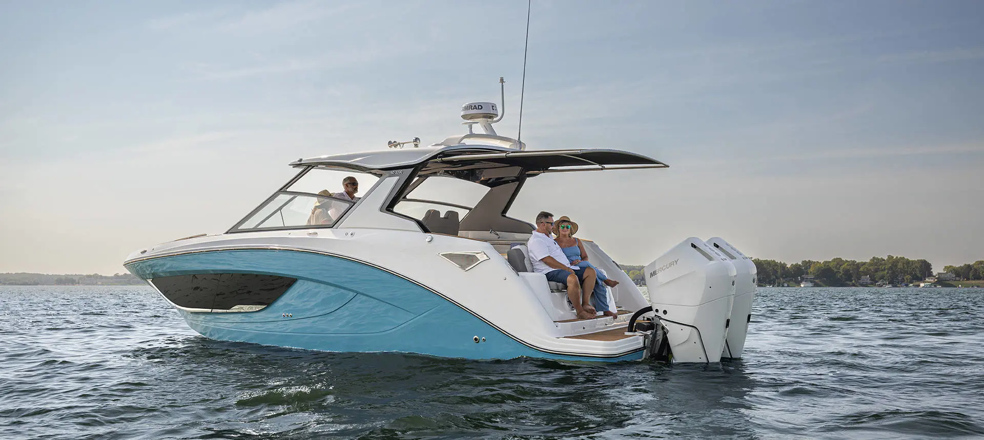 Couple sitting on rear seating of a parked Hurricane 3200 Outboard boat.