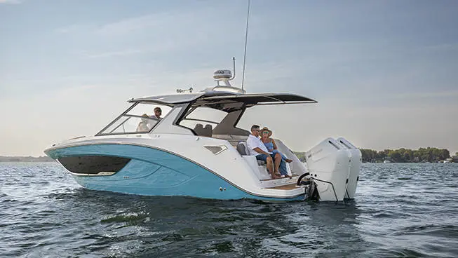 Couple sitting on rear seating of a parked Hurricane 3200 Outboard boat.