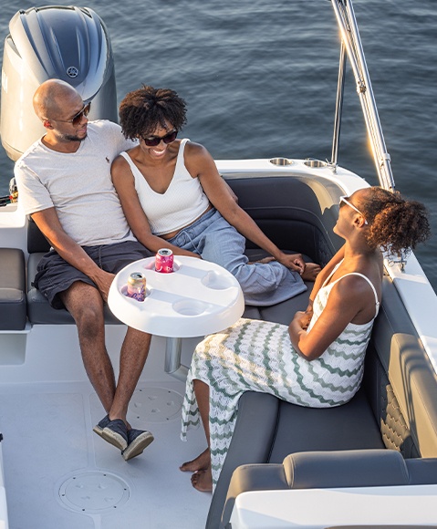 Friends laugh around functional table on a Hurricane SunDeck Sport boat.