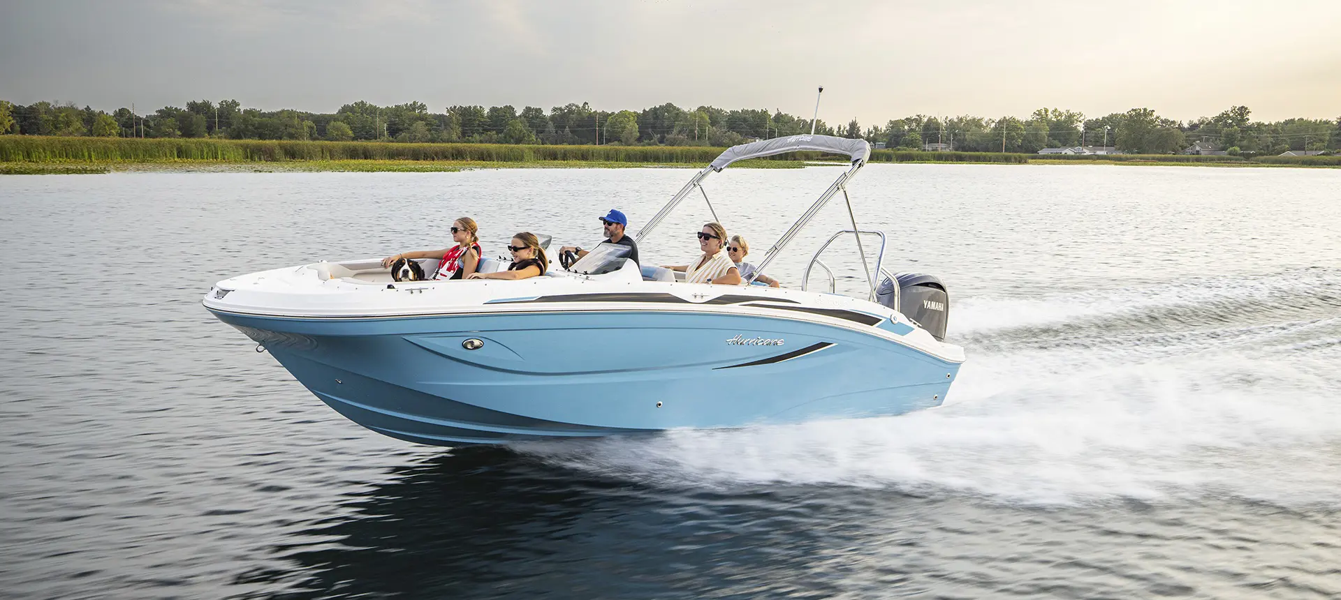 Family speeding across lake on Hurricane SunDeck Sport boat.
