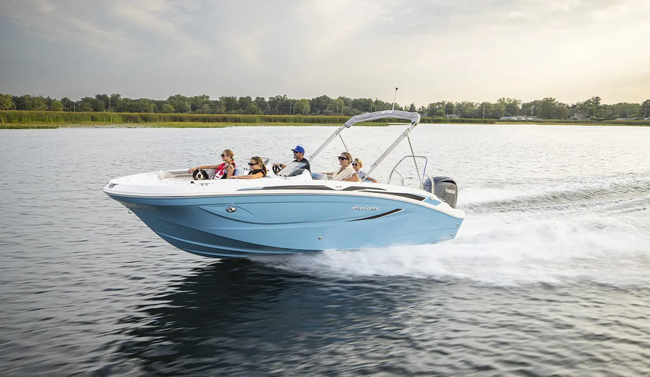 Family speeding across lake on Hurricane SunDeck Sport boat.