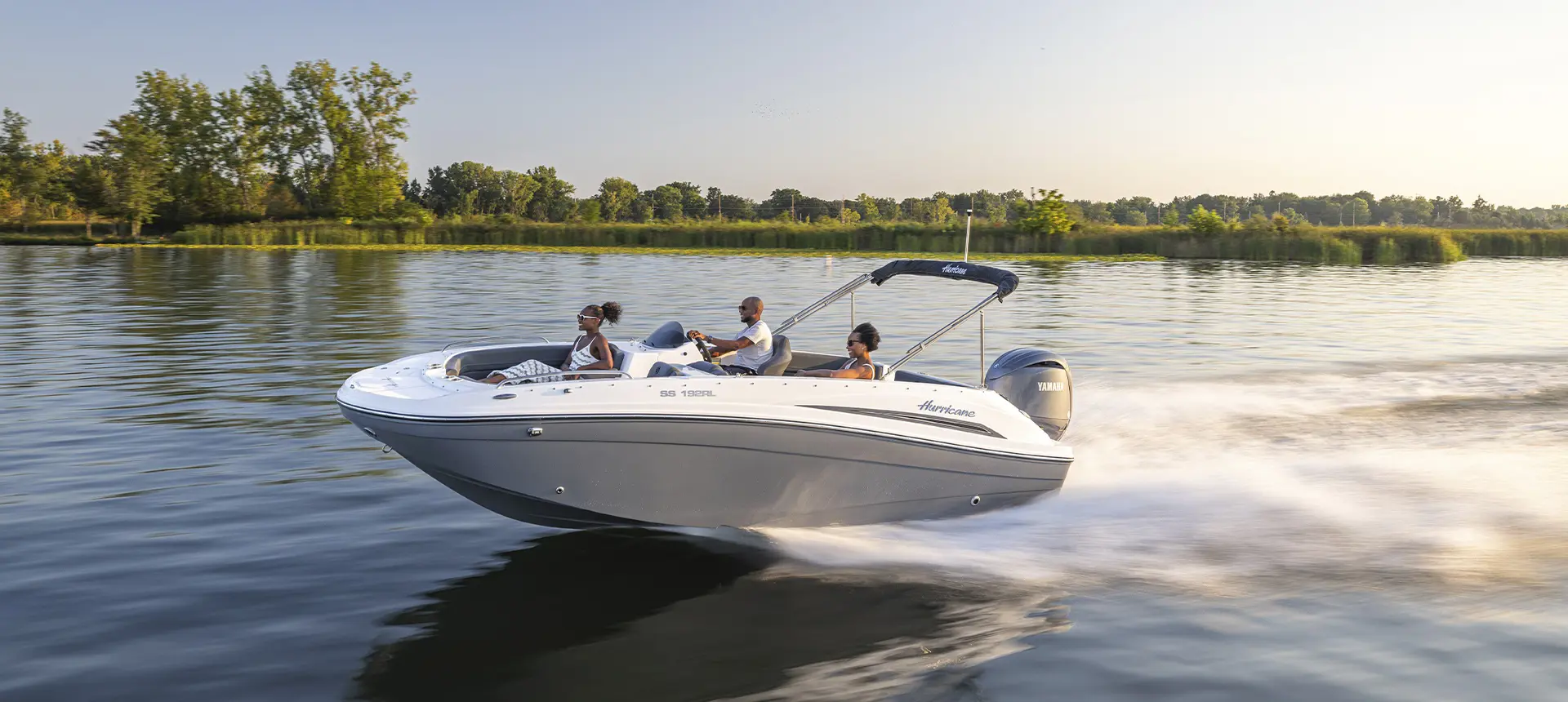 Friends speeding across water on a Hurricane SunDeck Sport boat.