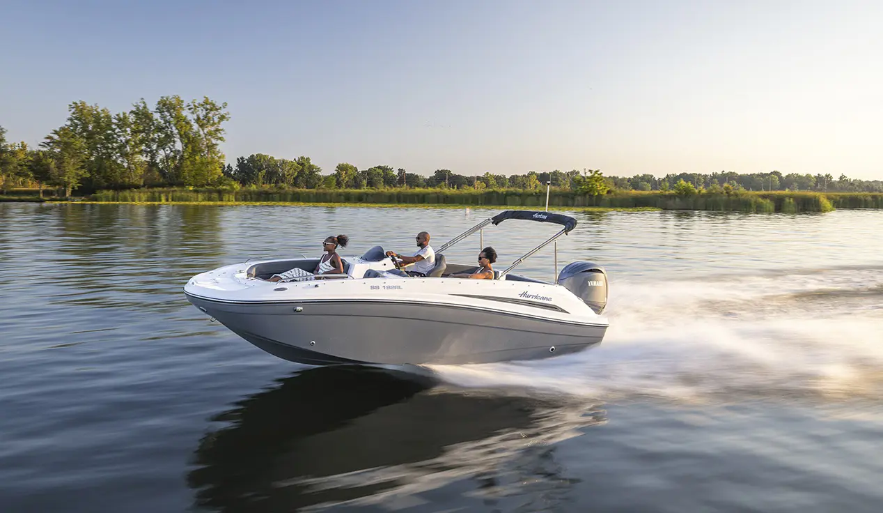 Friends speeding across water on a Hurricane SunDeck Sport boat.