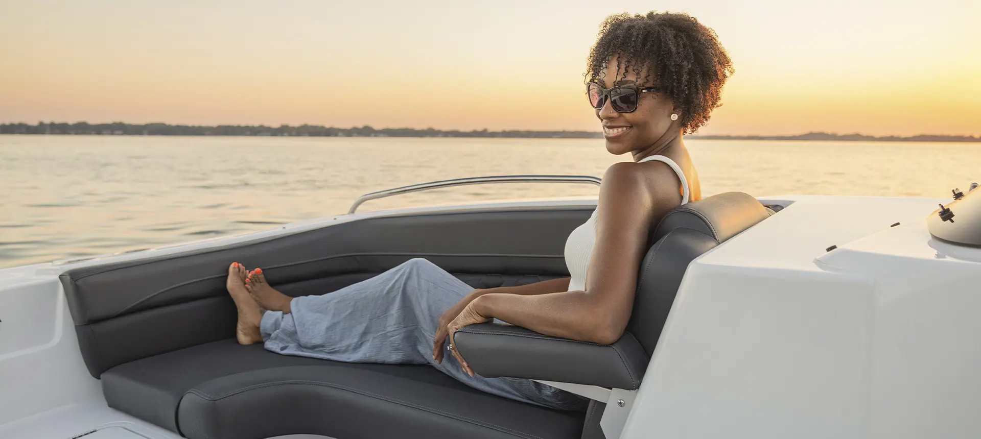 Woman simles in front seating of a Hurricane SunDeck Sport boat.