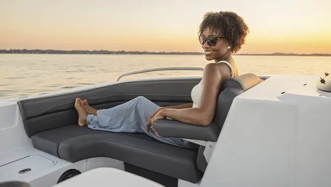 Woman simles in front seating of a Hurricane SunDeck Sport boat.