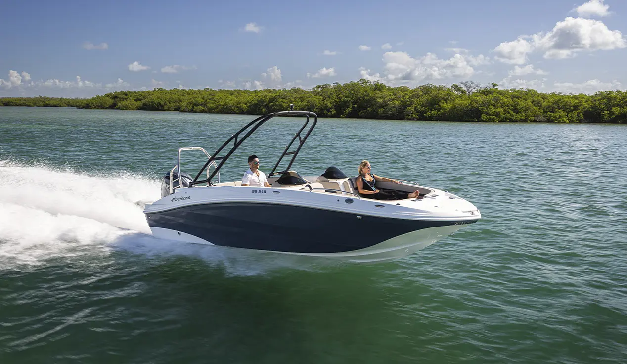 Couple speeding across blue water on a Hurricane SunDeck Sport boat.