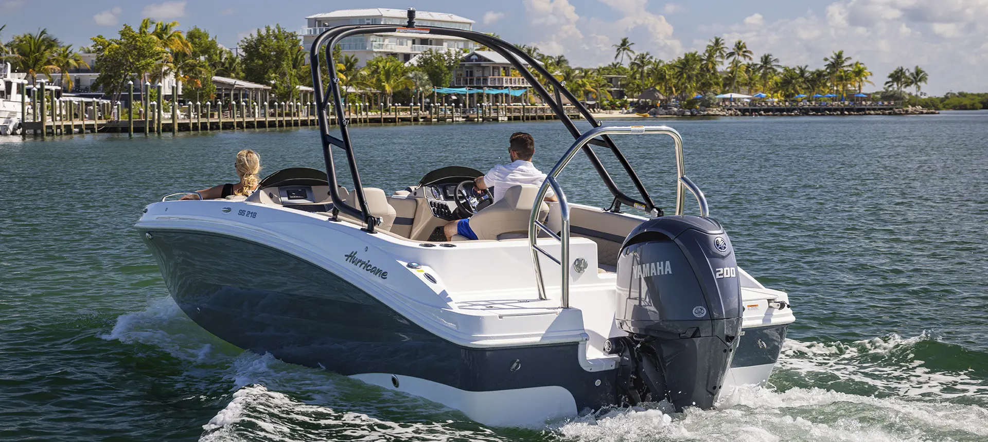 Rear view of a couple approaching shore on a Hurricane SunDeck Sport boat.